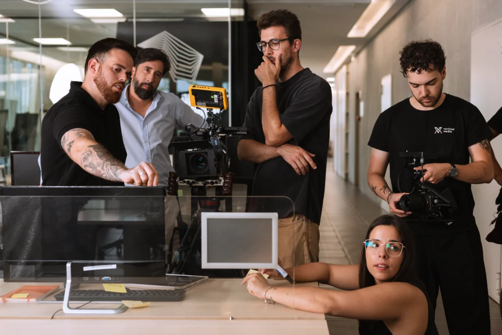 Equipa reunida em torno de uma câmara e de um computador durante uma filmagem.