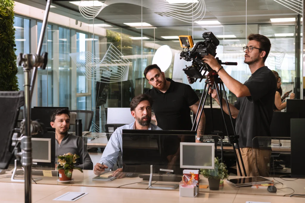 Equipa de produção audiovisual com câmaras e iluminação, num escritório.