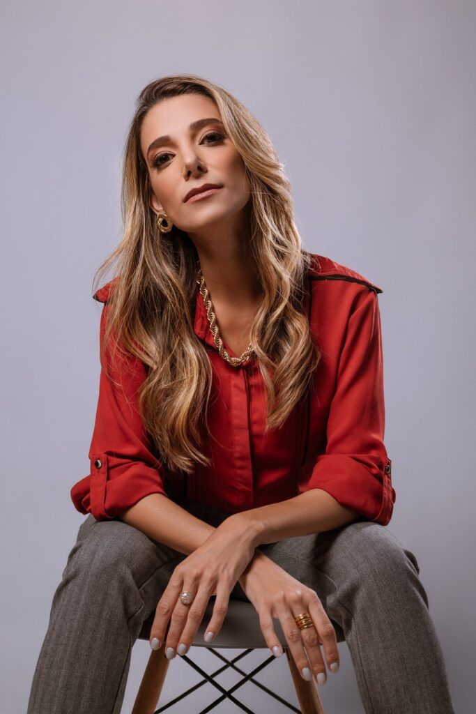 Mulher de camisa vermelha sentada num banco, numa pose conduzida durante a sessão de fotografia.