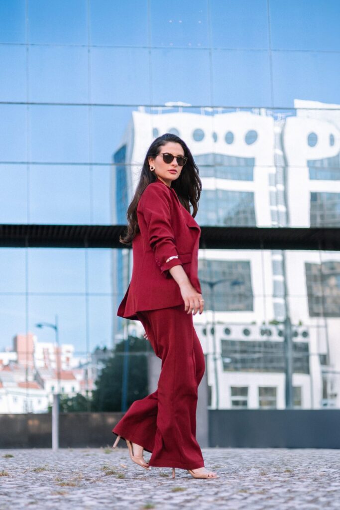 Mulher de fato bordô a caminhar em frente a um edifício de vidro, em Lisboa.