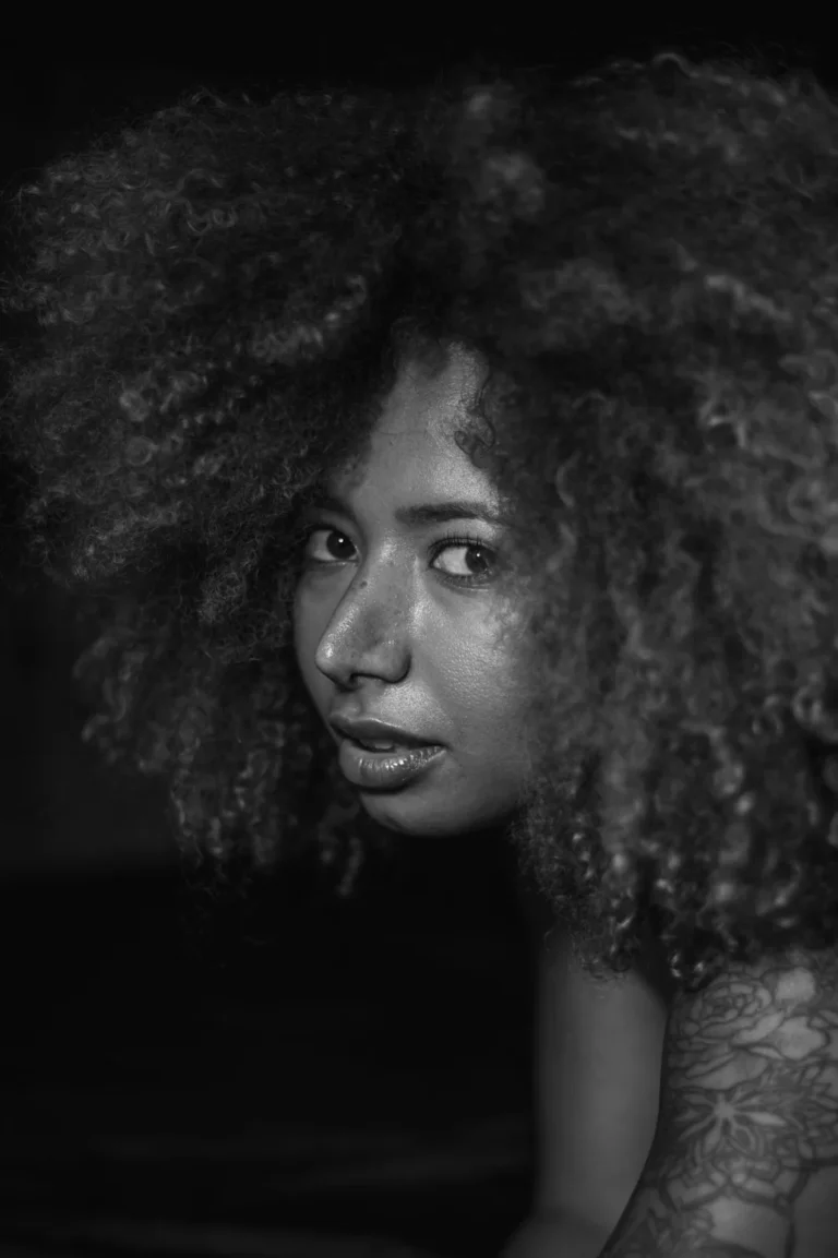 Retrato aproximado, a preto e branco, de uma mulher de cabelo afro com o olhar de lado.